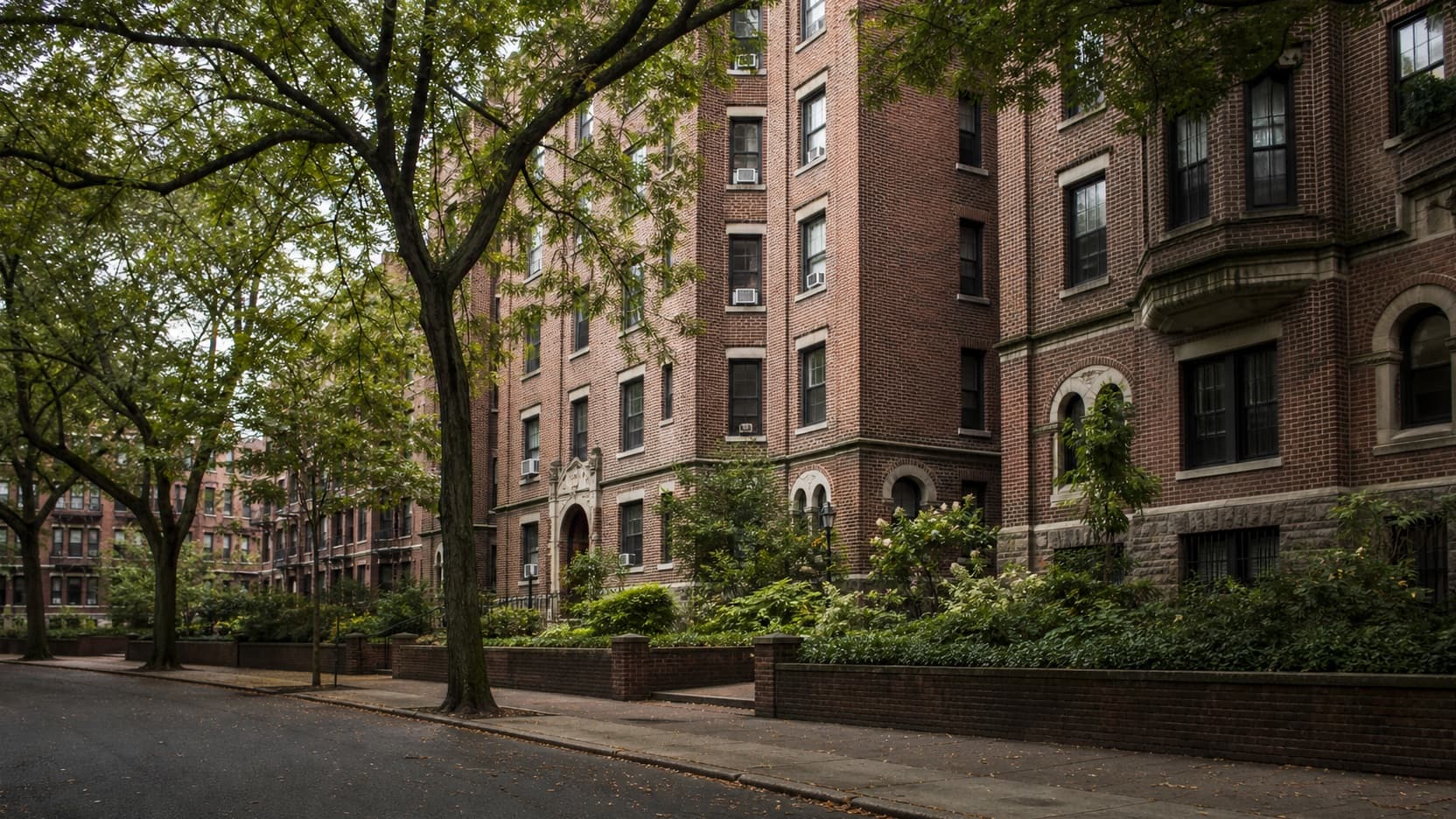 A street of prewar brick garden apartment buildings with arched entryways